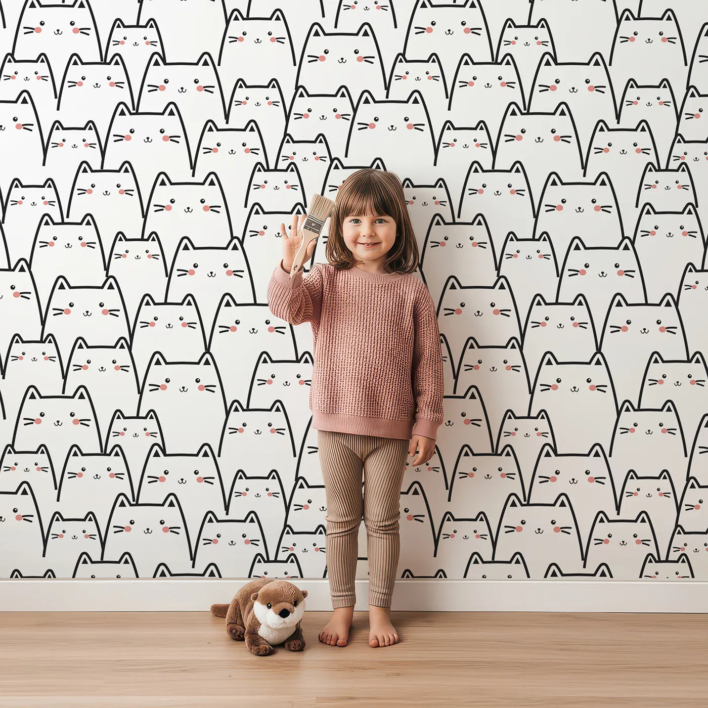 Lovely child standing in front of Whimsy Tots Crowd of Cats Wallpaper in White with cat, cheek, whisker in design.