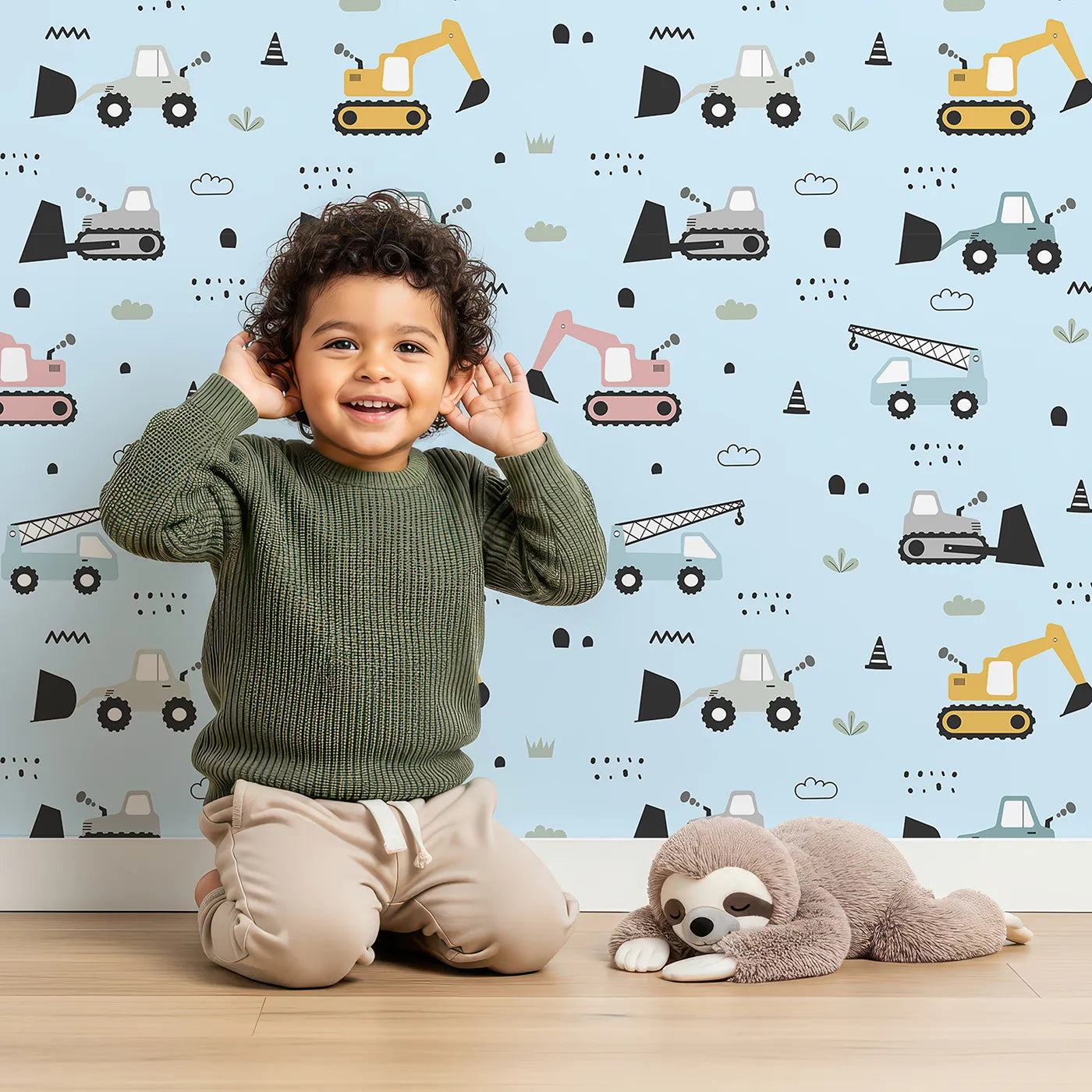 Lovely child standing in front of Whimsy Tots Digger Parade Wallpaper in Blue with crane, digger, loader, truck, cone in design.