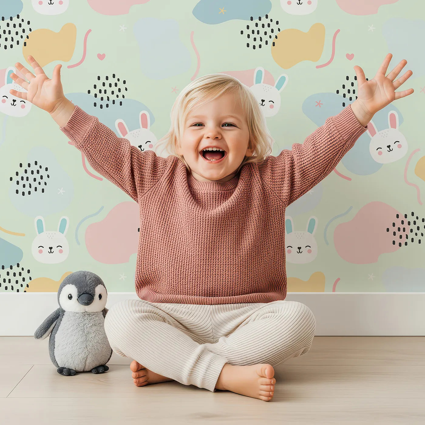Lovely child standing in front of Whimsy Tots Bunny Bounce Abstract Wallpaper in Mint Green with bunny, blob, heart, texture in design.