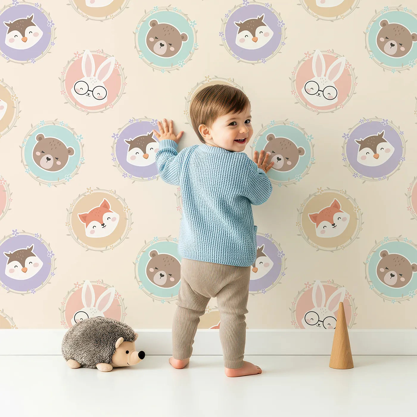Lovely child standing in front of Whimsy Tots Woodland Buddy Portraits Wallpaper in Buttercream with bear, fox, owl, bunny, flower, wreath in design.