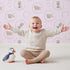 Lovely child standing in front of Whimsy Tots Safari Nap Bubbles Wallpaper in Lilac Lavender with elephant, zebra, lion, giraffe, hippo, bubble, circle in design. Lovely child standing in front of Whimsy Tots Safari Nap Bubbles Wallpaper in Lilac Lavender with elephant, zebra, lion, giraffe, hippo, bubble, circle in design.