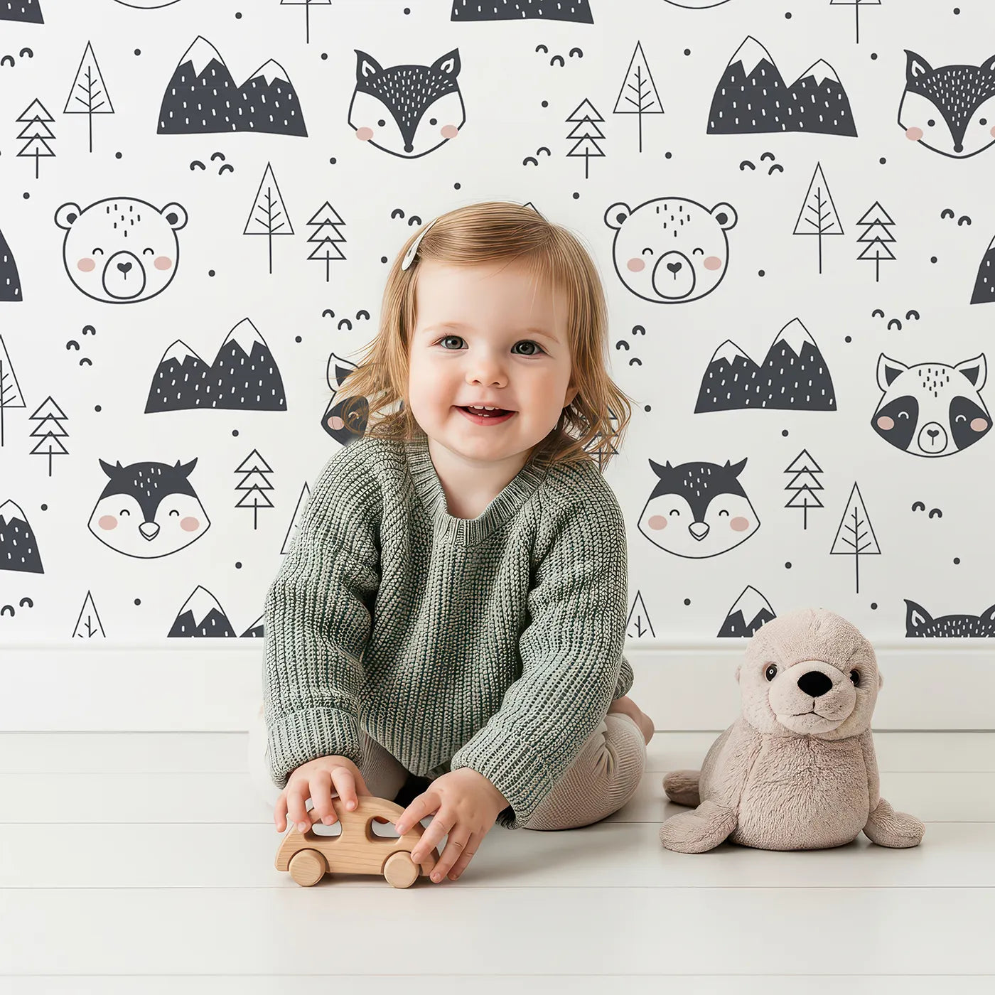 Lovely child standing in front of Whimsy Tots Woodland Peekaboo Friends Wallpaper with bear, owl, fox, raccoon, mountain, tree in design.