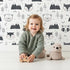 Lovely child standing in front of Whimsy Tots Woodland Peekaboo Friends Wallpaper with bear, owl, fox, raccoon, mountain, tree in design. Lovely child standing in front of Whimsy Tots Woodland Peekaboo Friends Wallpaper with bear, owl, fox, raccoon, mountain, tree in design.
