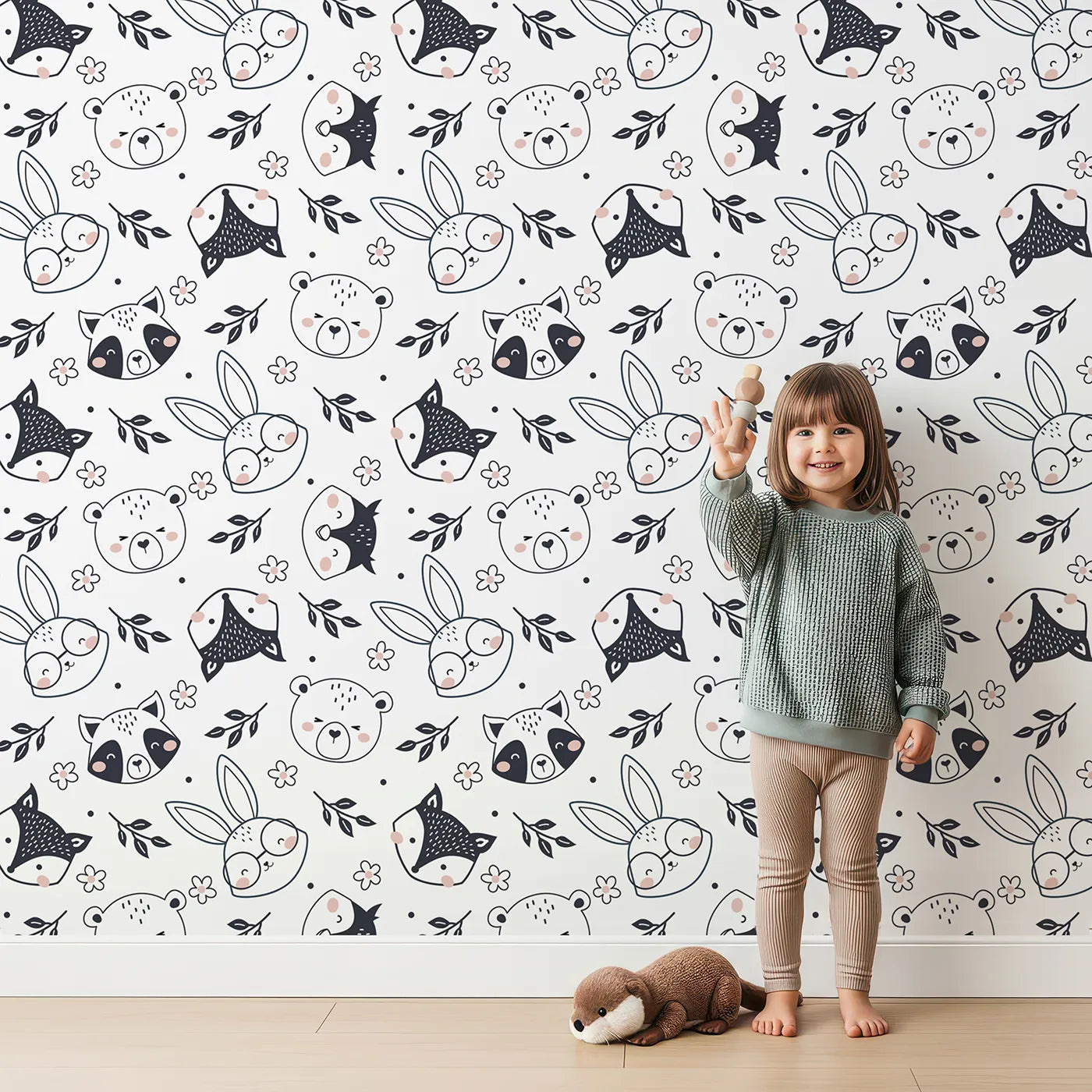 Lovely child standing in front of Whimsy Tots Woodland Scribble Friends Wallpaper in Monochrome with bear, bunny, fox, raccoon, flower, leaf in design.