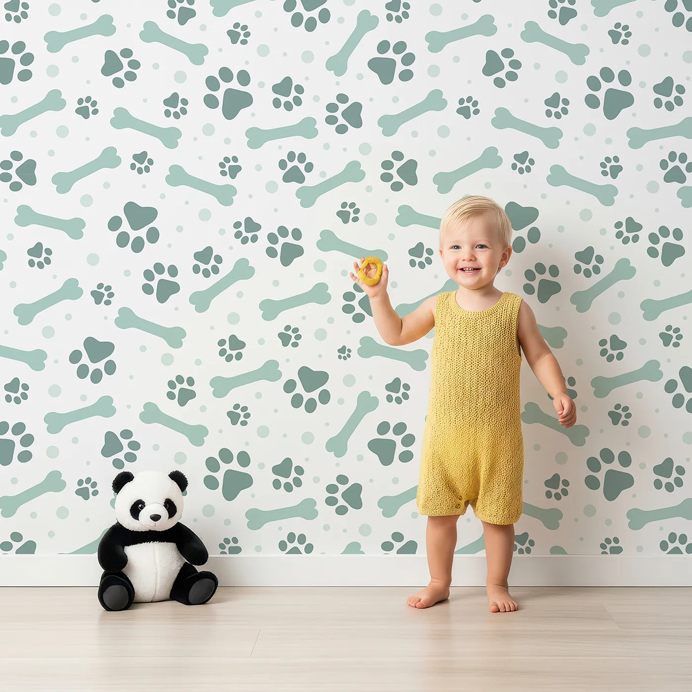 Lovely child standing in front of Whimsy Tots Puppy Paw Parade Wallpaper in Mint Green with paw, bone, dot in design.