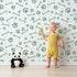 Lovely child standing in front of Whimsy Tots Puppy Paw Parade Wallpaper in Mint Green with paw, bone, dot in design. Lovely child standing in front of Whimsy Tots Puppy Paw Parade Wallpaper in Mint Green with paw, bone, dot in design.
