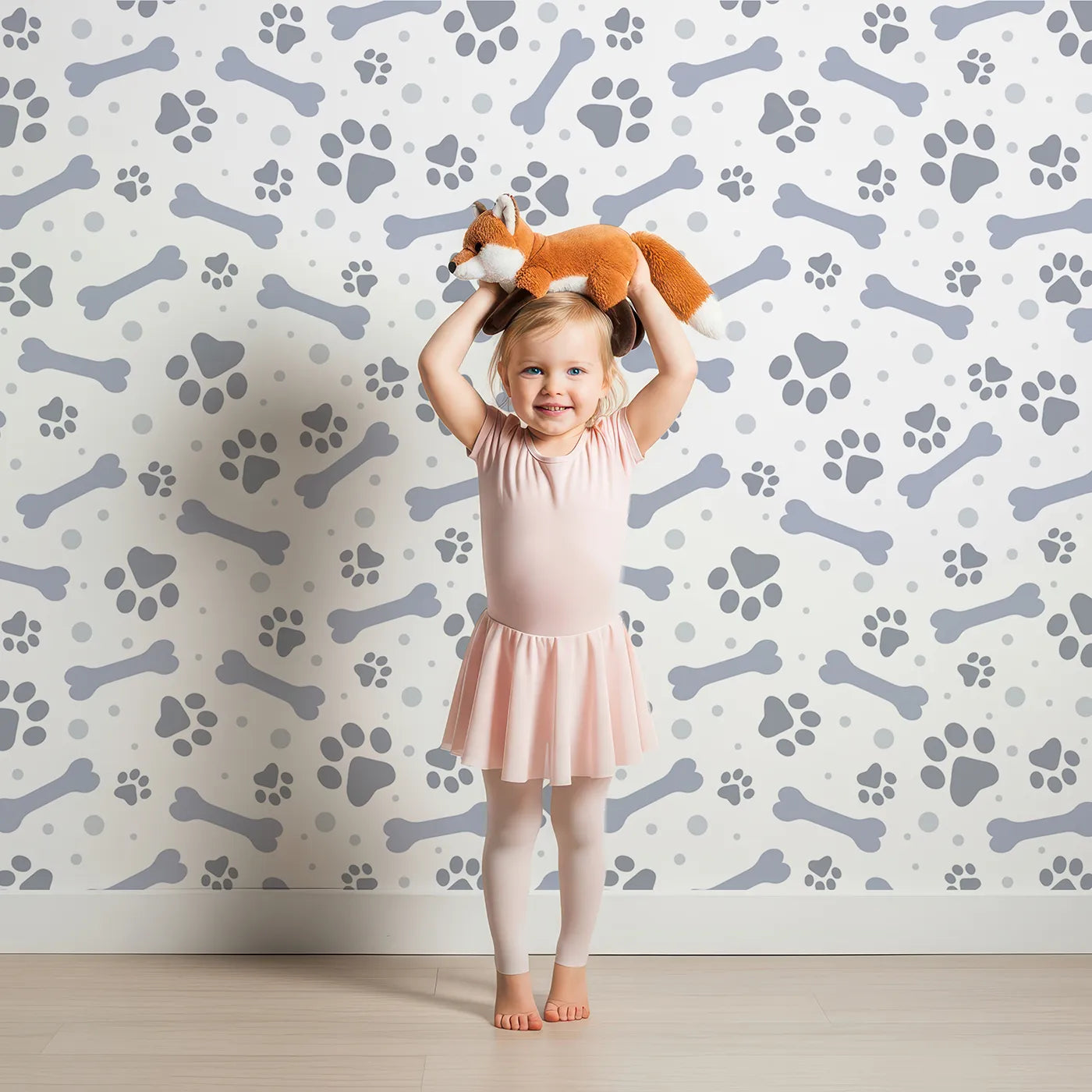 Lovely child standing in front of Whimsy Tots Puppy Paw Parade Wallpaper in Blue Gray with paw, bone, dot in design.