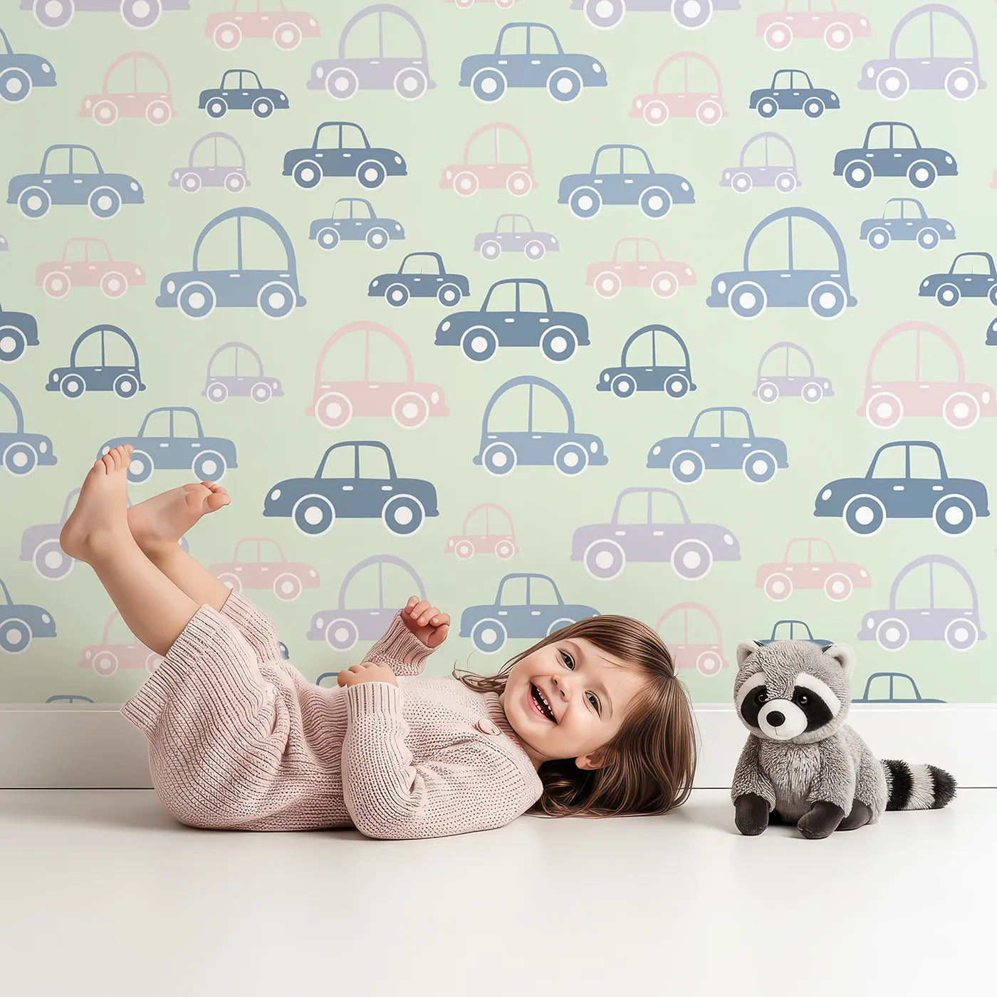 Lovely child standing in front of Whimsy Tots Tiny Toot Toot Cars Wallpaper in Sage Green with car, vehicle, pastel, transportation in design.