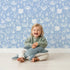 Lovely child standing in front of Whimsy Tots Coral Garden Dance Wallpaper in Ocean Blue with coral, seaweed, starfish, bubble in design. Lovely child standing in front of Whimsy Tots Coral Garden Dance Wallpaper in Ocean Blue with coral, seaweed, starfish, bubble in design.
