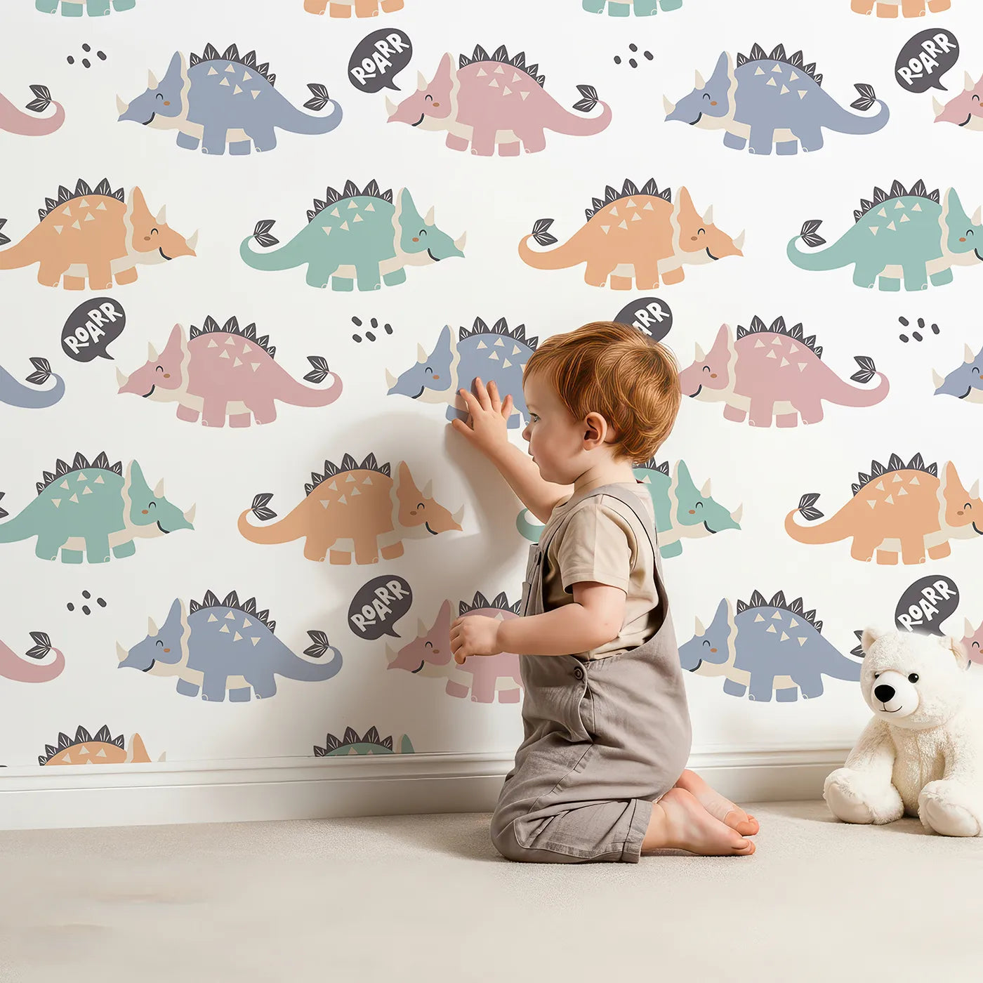 Lovely child standing in front of Whimsy Tots Roar and Stomp Dinosaurs Wallpaper with dinosaur, horn, speech bubble, scale, tail in design.