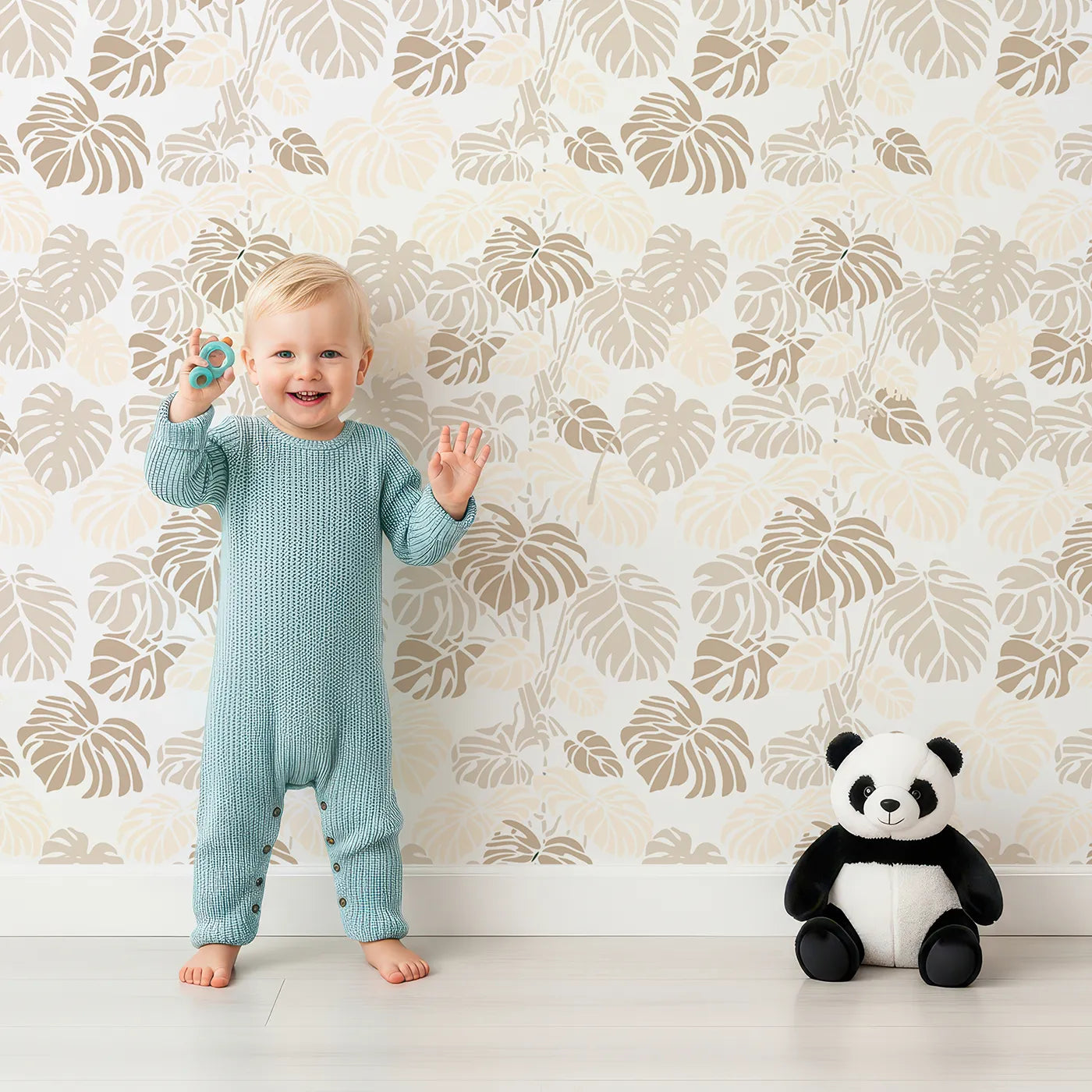 Lovely child standing in front of Whimsy Tots Monstera Jungle Wallpaper in Sandstone Beige with leaf, monstera, jungle, foliage in design.