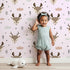 Lovely child standing in front of Whimsy Tots Woodland Deer Wallpaper in Blush Pink with deer, cloud, tree, snowflake in design. Lovely child standing in front of Whimsy Tots Woodland Deer Wallpaper in Blush Pink with deer, cloud, tree, snowflake in design.
