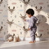 Lovely child standing in front of Whimsy Tots Woodland Deer Wallpaper in Cream with deer, cloud, tree, snowflake in design. Lovely child standing in front of Whimsy Tots Woodland Deer Wallpaper in Cream with deer, cloud, tree, snowflake in design.