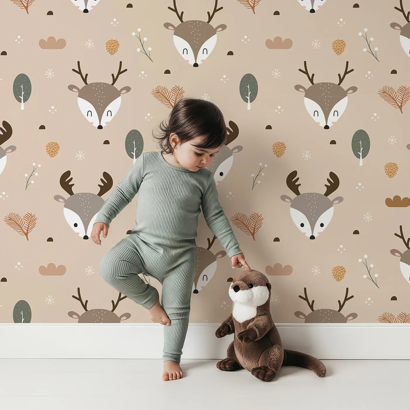 Lovely child standing in front of Whimsy Tots Forest Forager Deer Wallpaper in Beige with deer, pinecone, tree, snowflake, berry in design.