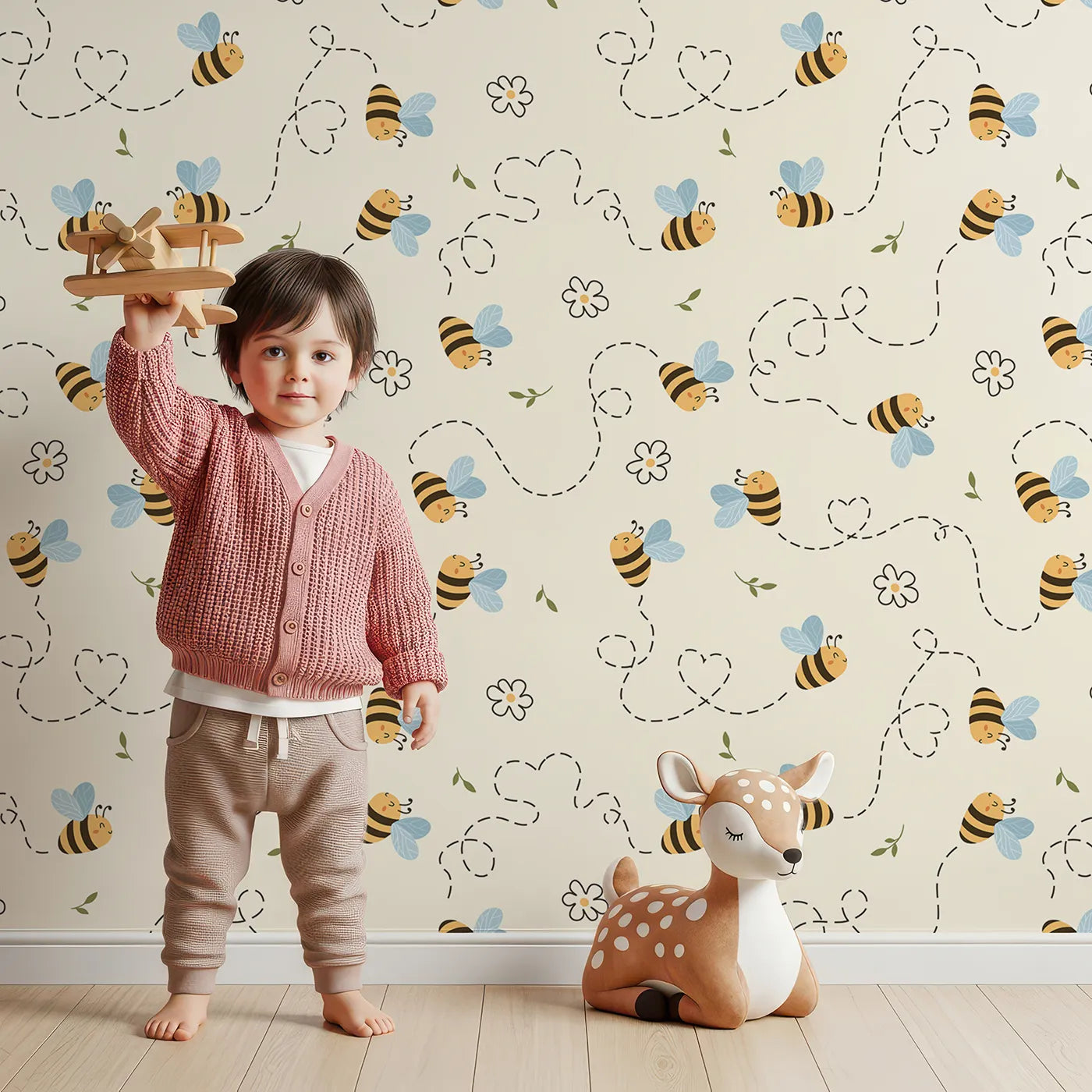 Lovely child standing in front of Whimsy Tots Busy Bee Trail Wallpaper in Buttercream with bee, flower, leaf, heart, trail in design.