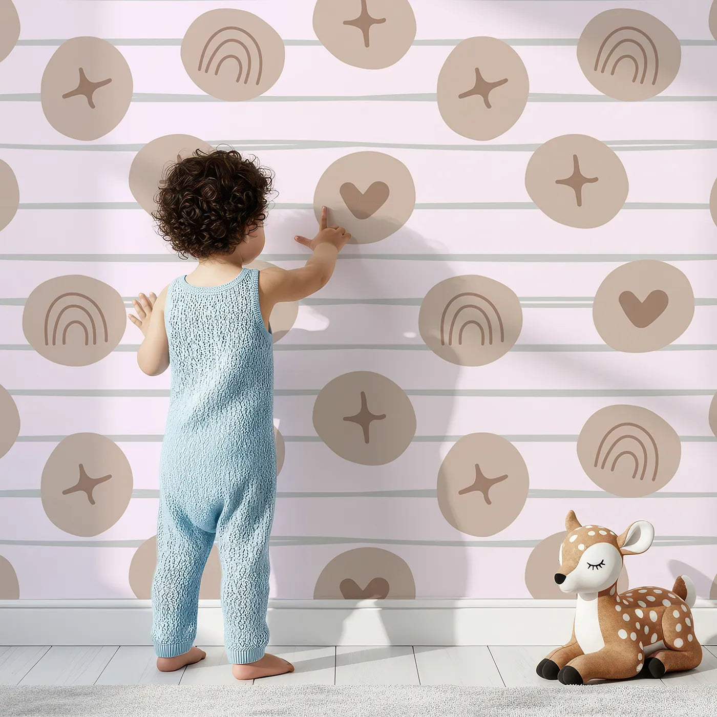 Lovely child standing in front of Whimsy Tots Boho Rhythm Doodle Wallpaper in Soft Blush Pink with rainbow, heart, star, stripe, doodle in design.