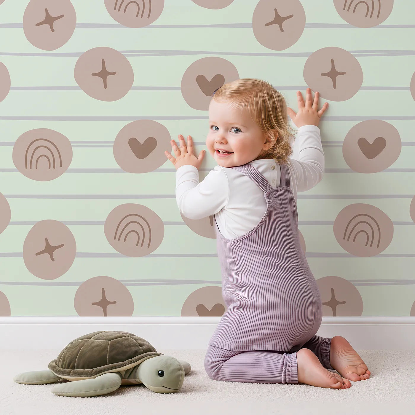 Lovely child standing in front of Whimsy Tots Boho Rhythm Doodle Wallpaper in Mint Green with rainbow, heart, star, stripe, doodle in design.