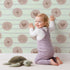 Lovely child standing in front of Whimsy Tots Boho Rhythm Doodle Wallpaper in Mint Green with rainbow, heart, star, stripe, doodle in design. Lovely child standing in front of Whimsy Tots Boho Rhythm Doodle Wallpaper in Mint Green with rainbow, heart, star, stripe, doodle in design.