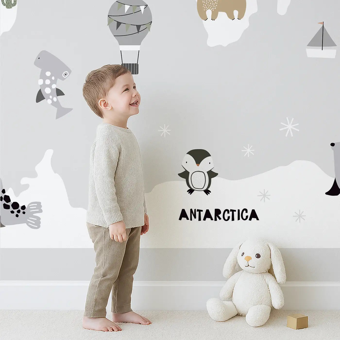 Child in front of Whimsy Tots Whimsy World Map Wall Mural with map, animal, whale, lion, kangaroo, elephant, crocodile, penguin, bear in design.