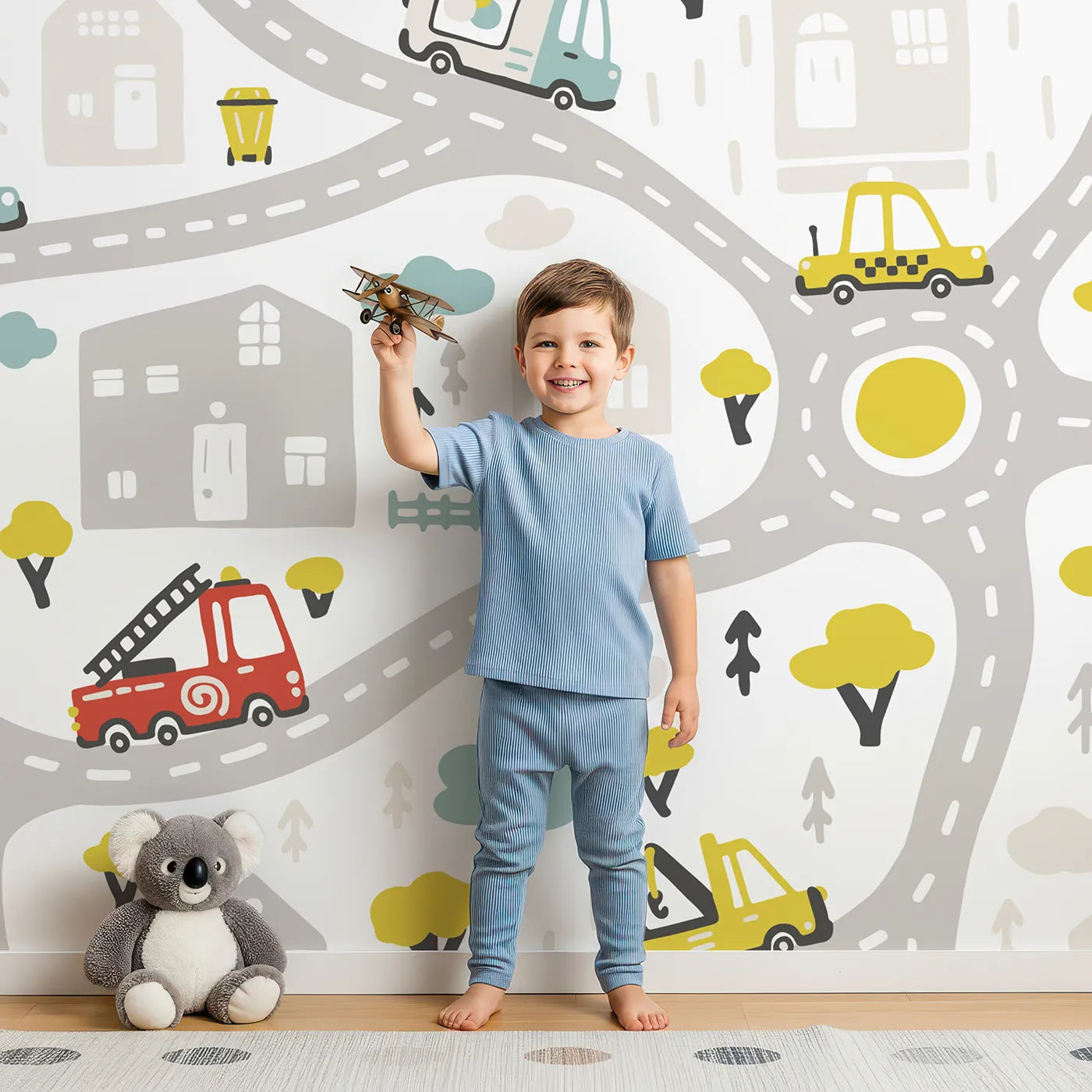 Child in front of Whimsy Tots Busy Town Emergency Vehicles Wall Mural with car, truck, fire truck, ambulance, police car, road, town, city in design.