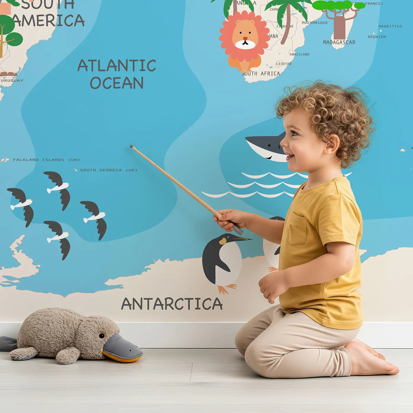 Child in front of Whimsy Tots Animal World Map Adventure Wall Mural with map, world, animal, continent, ocean, nature, educational, cartoon in design.