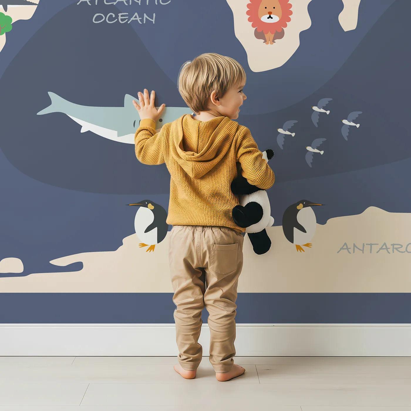 Child in front of Whimsy Tots Cartoon World Map Adventure Wall Mural with map, world, animal, ocean, travel, educational, cartoon, continent in design.