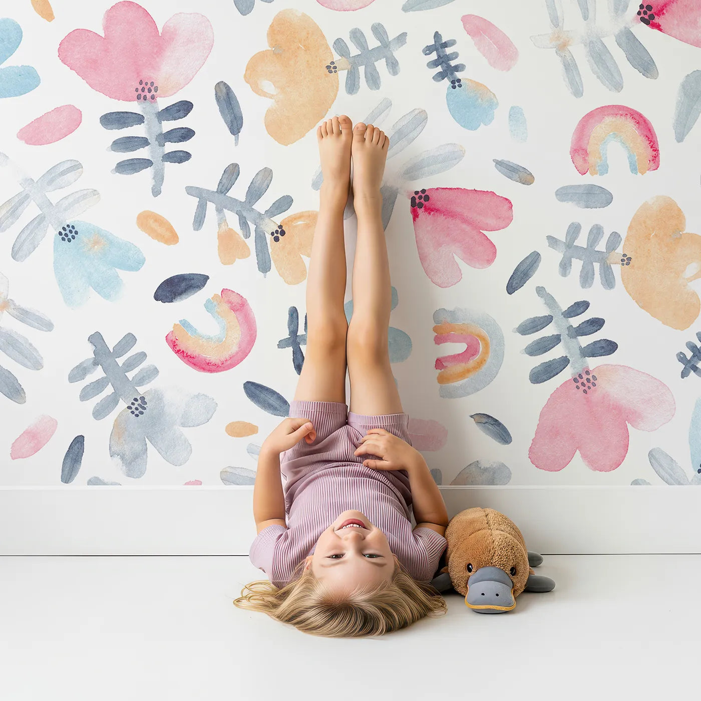 Child in front of Whimsy Tots Pastel Rainbow Garden Wall Mural with flower, rainbow, pastel, watercolor, abstract, floral, pink, blue in design.