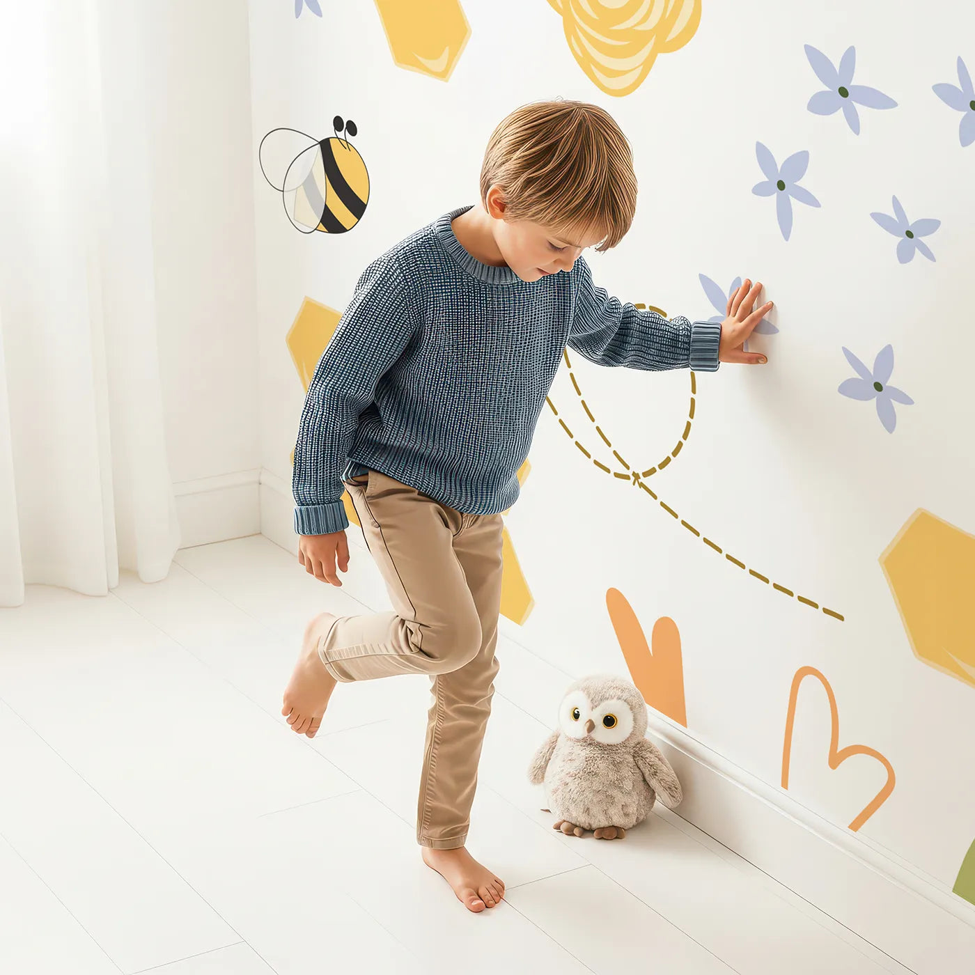 Child in front of Whimsy Tots Happy Bee Garden Wall Mural with bee, honeycomb, flower, heart, yellow, cute, cartoon, honey in design.