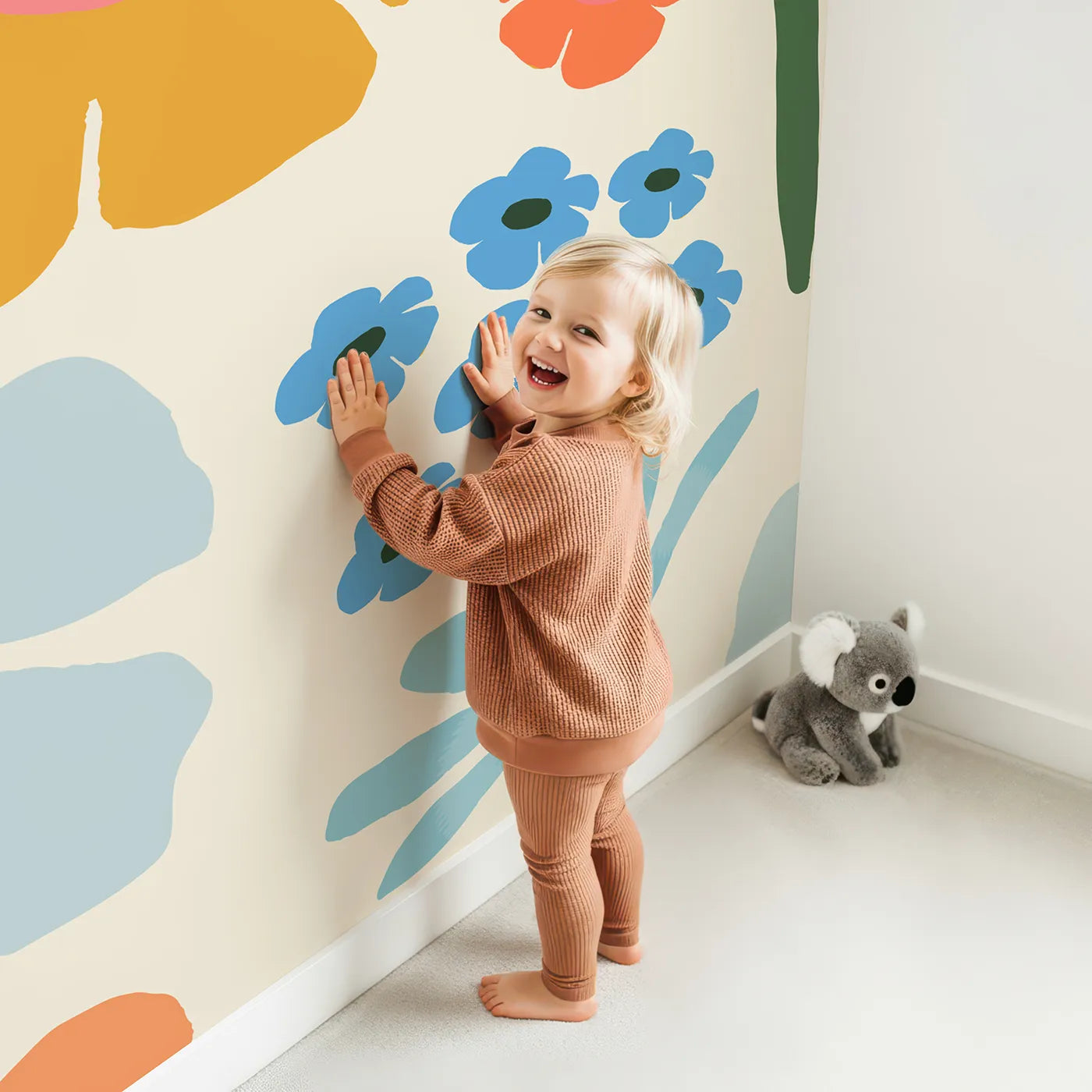 Child in front of Whimsy Tots Retro Sixties Floral Wall Mural with flower, retro, vintage, 60s, 70s, floral, orange, blue in design.