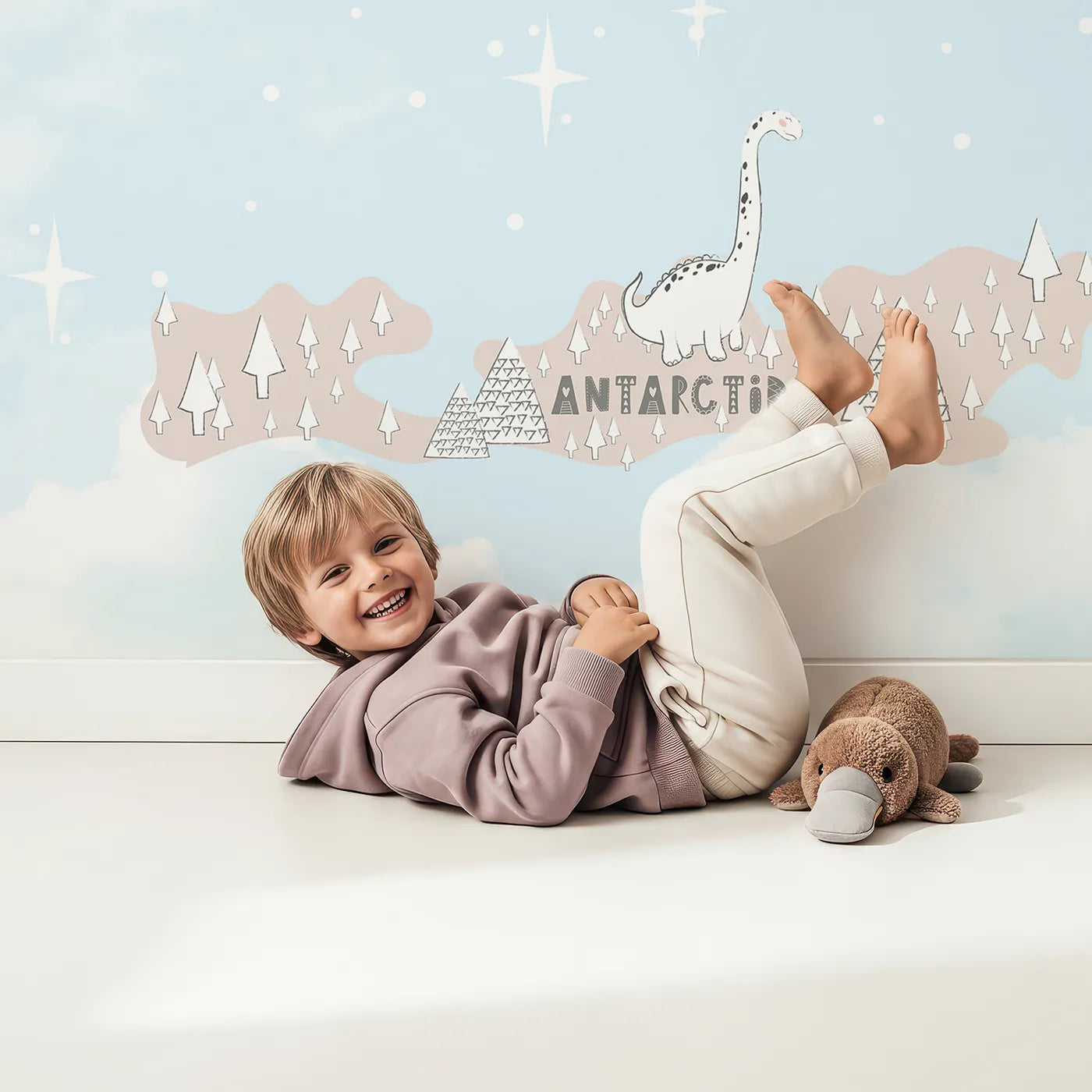 Child in front of Whimsy Tots Doodle Dinosaur World Map Wall Mural with dinosaur, map, world, cute, pastel, pink, blue, prehistoric in design.