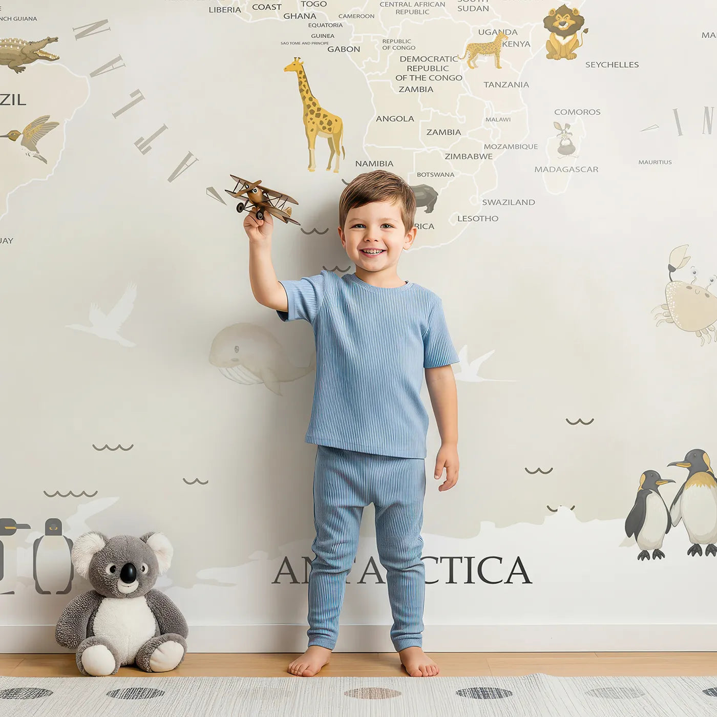 Child in front of Whimsy Tots Neutral Animal World Map Wall Mural with map, world, animal, neutral, beige, modern, silhouette, educational in design.