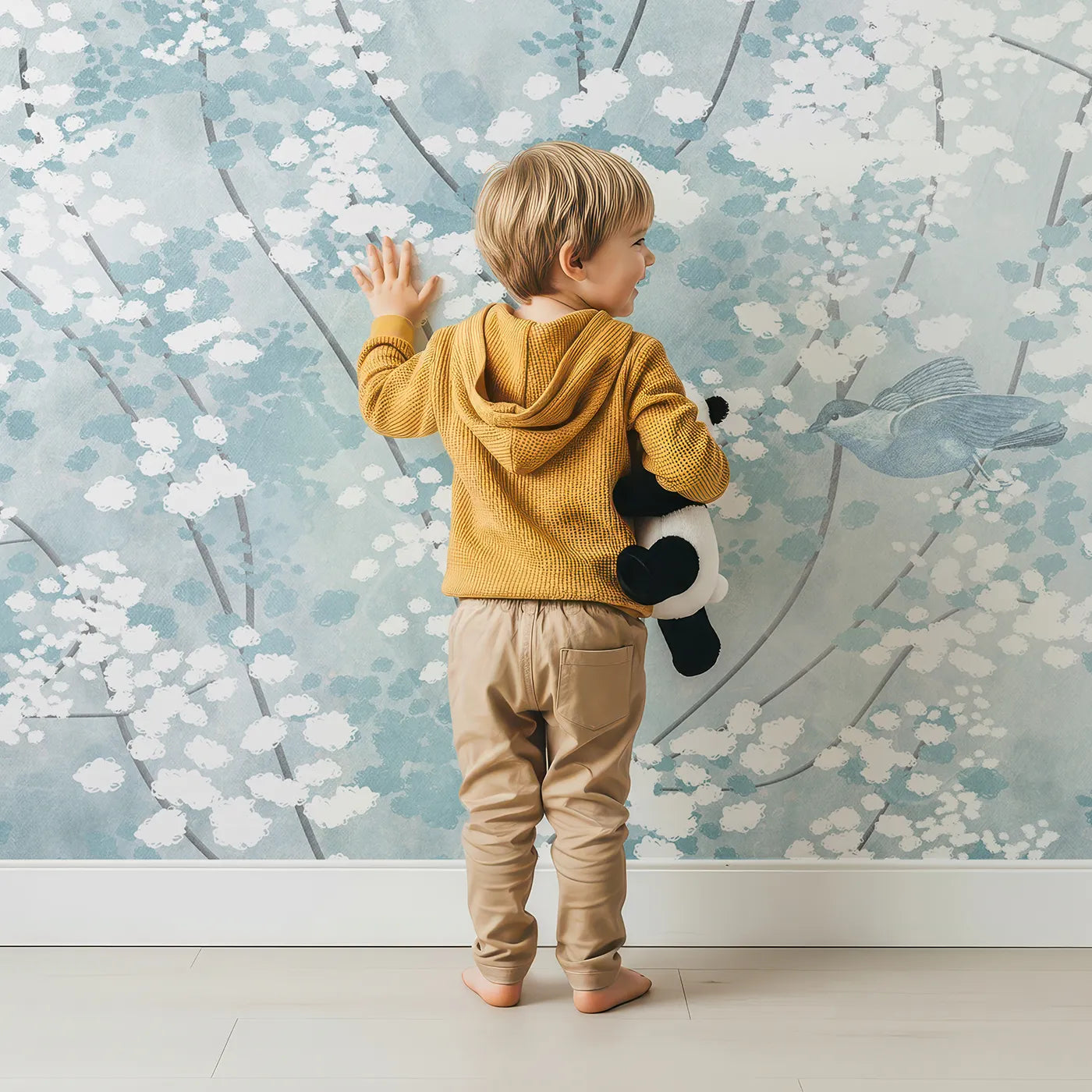 Child in front of Whimsy Tots Winter Blossom Wall Mural with flower, blossom, winter, blue, bird, snow, frost, painterly in design.