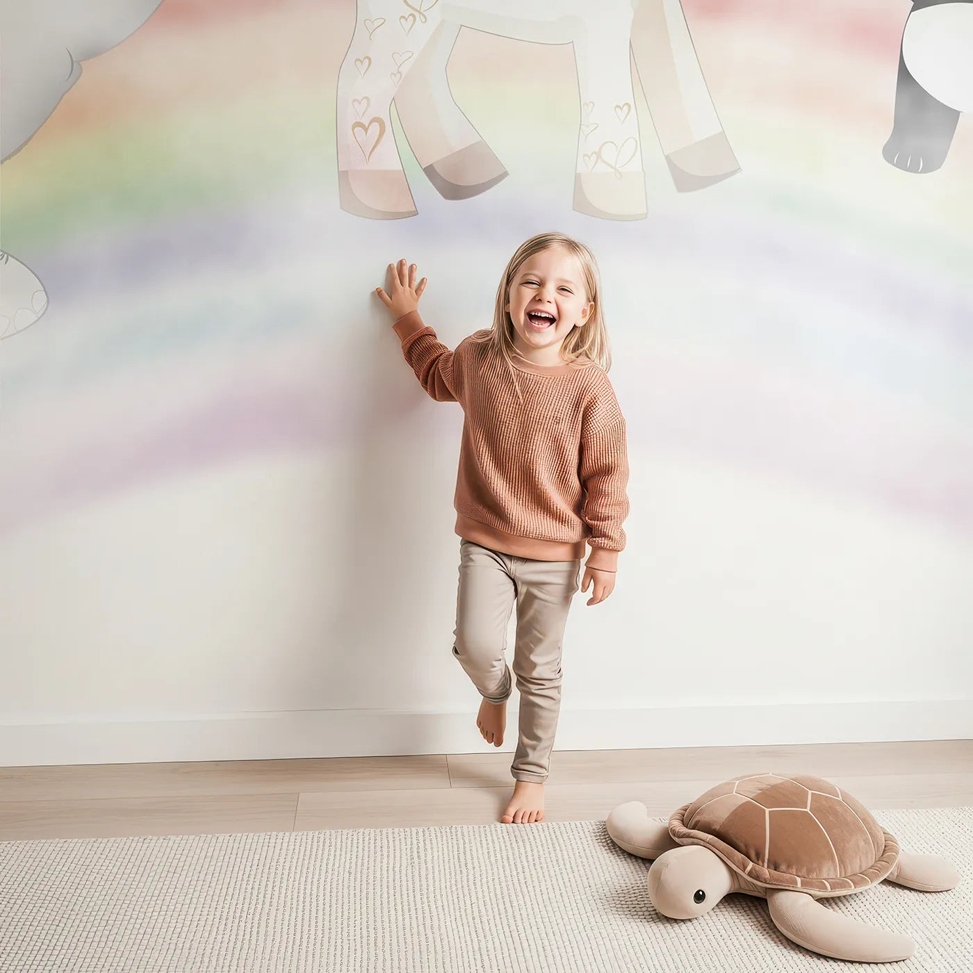 Child in front of Whimsy Tots Rainbow Friends Adventure Wall Mural with animal, safari, rainbow, cute, sky, star, balloon, pastel in design.