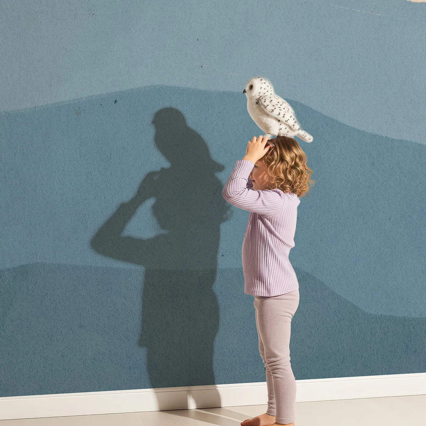 Child in front of Whimsy Tots Coastal Balloons Wall Mural with balloon, lighthouse, sea, hill, vintage, retro, blue, surreal in design.