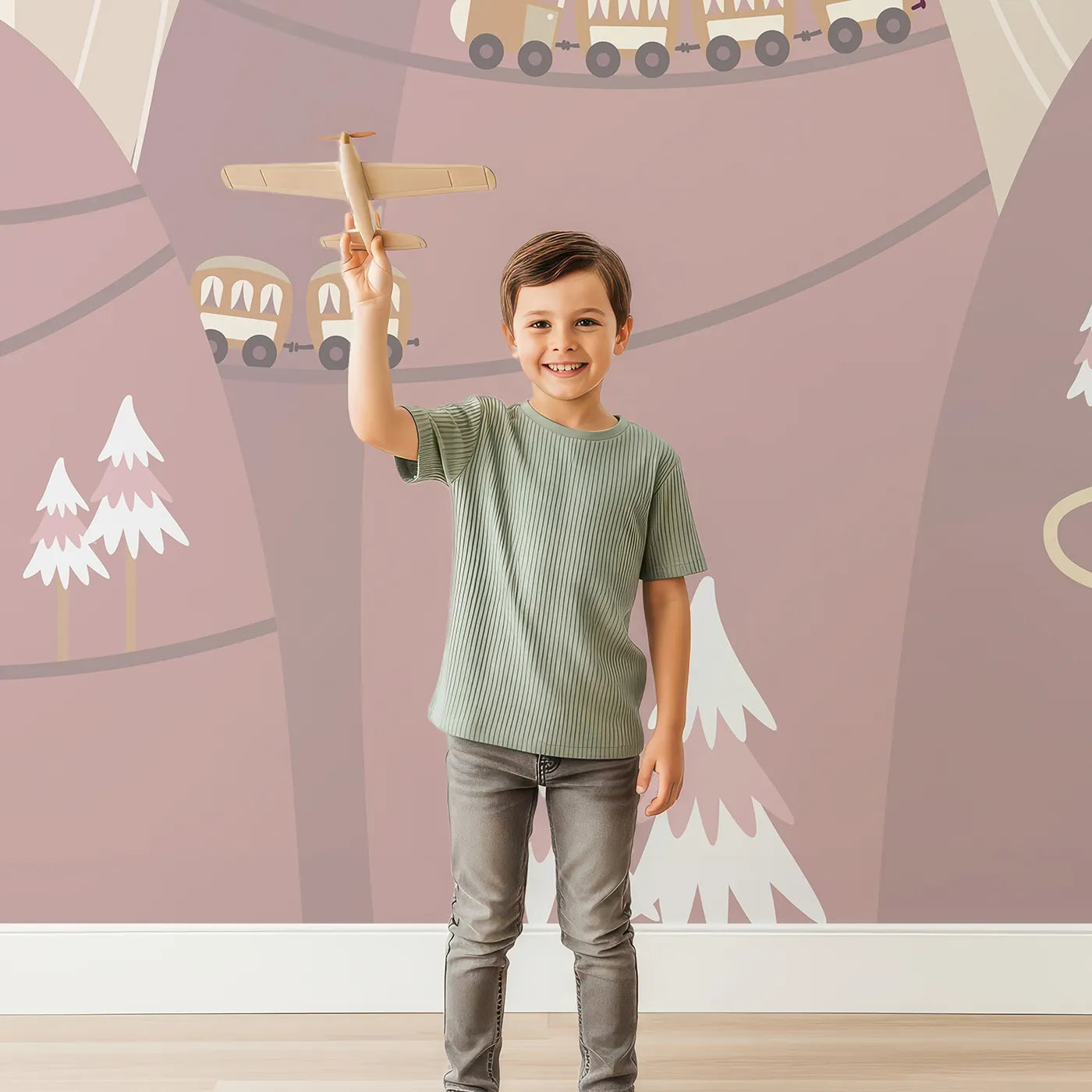 Child in front of Whimsy Tots Mountain Train Adventure Wall Mural in Pink with train, mountain, hill, house, hot air balloon, bridge, tree in design.