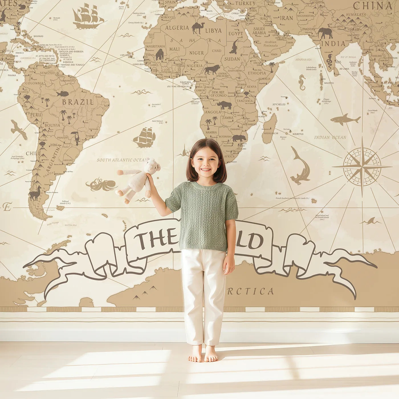 Child in front of Whimsy Tots Vintage World Map Wall Mural with map, world, vintage, sepia, travel, educational, animal, classic in design.