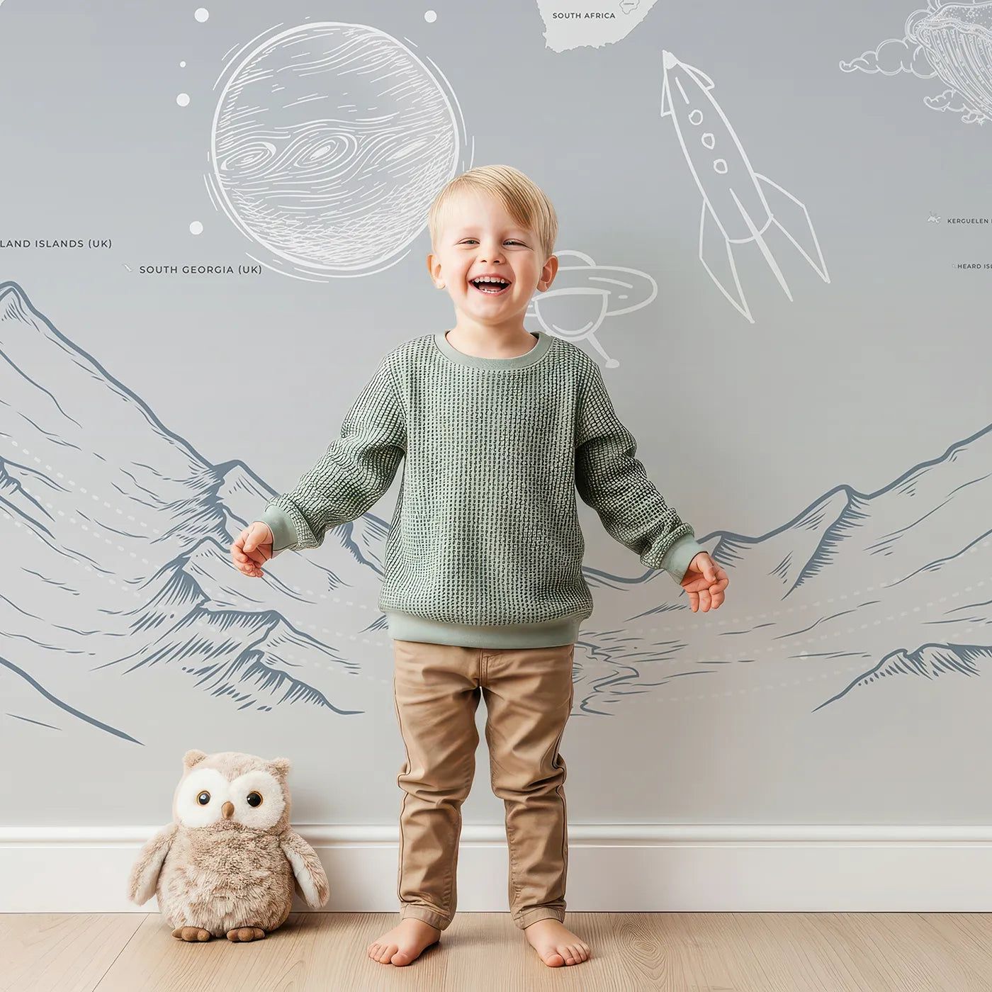 Child in front of Whimsy Tots Cosmic Explorer World Map Wall Mural in Blue with map, world, space, rocket, planet, mountain, blue, sketch in design.