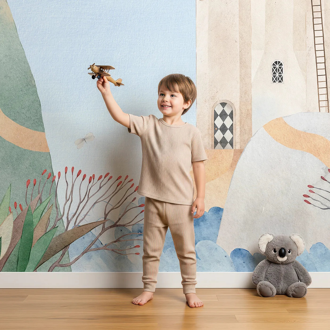 Child in front of Whimsy Tots Whimsical Castle Village Wall Mural with castle, whimsical, watercolor, adventure, tree, fantasy, cute, storybook in design.
