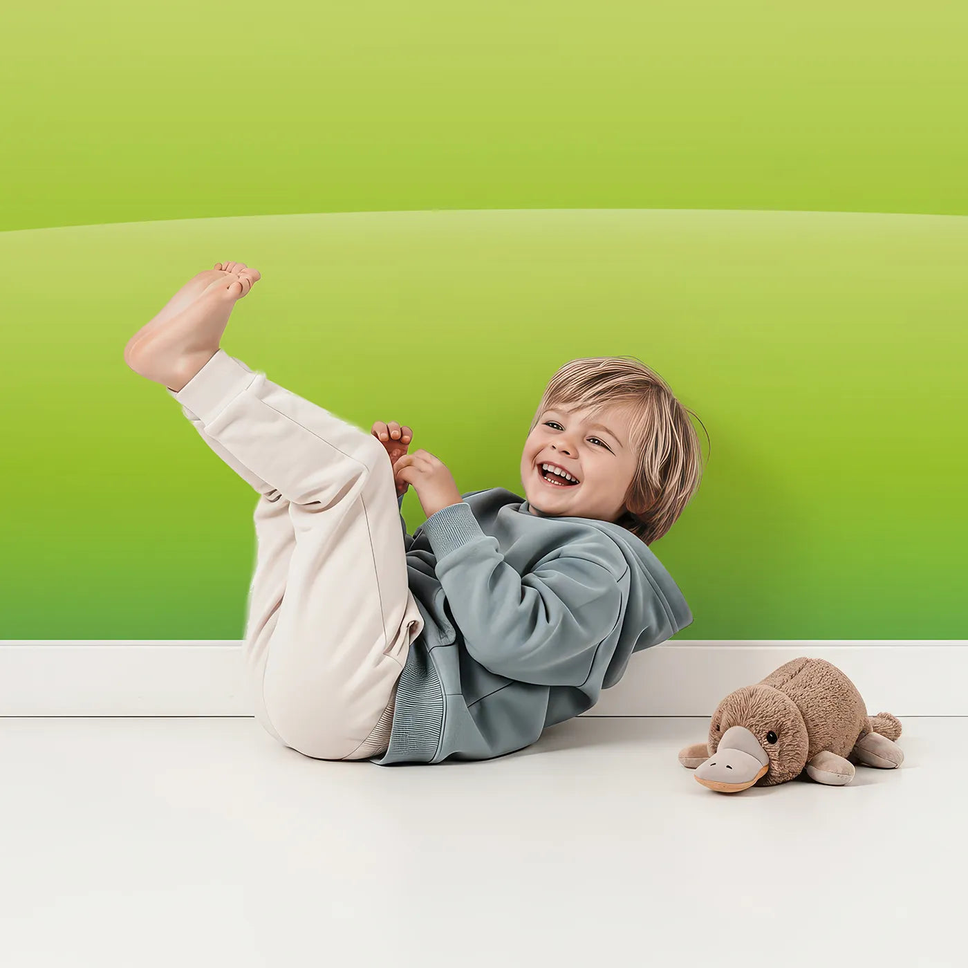 Child in front of Whimsy Tots Rainbow Meadow Wall Mural with rainbow, meadow, landscape, green, sky, colorful, simple, cartoon in design.
