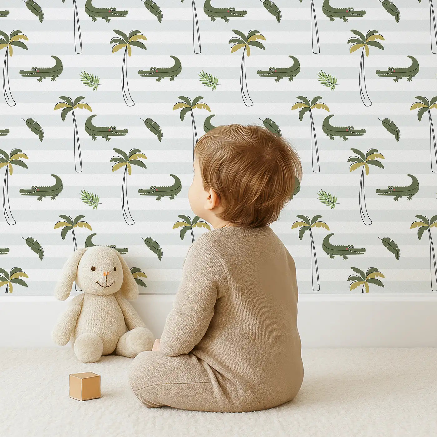 Child in front of Whimsy Tots Tropical Crocodile Haven Wallpaper with crocodile, palm tree, stripe in design.