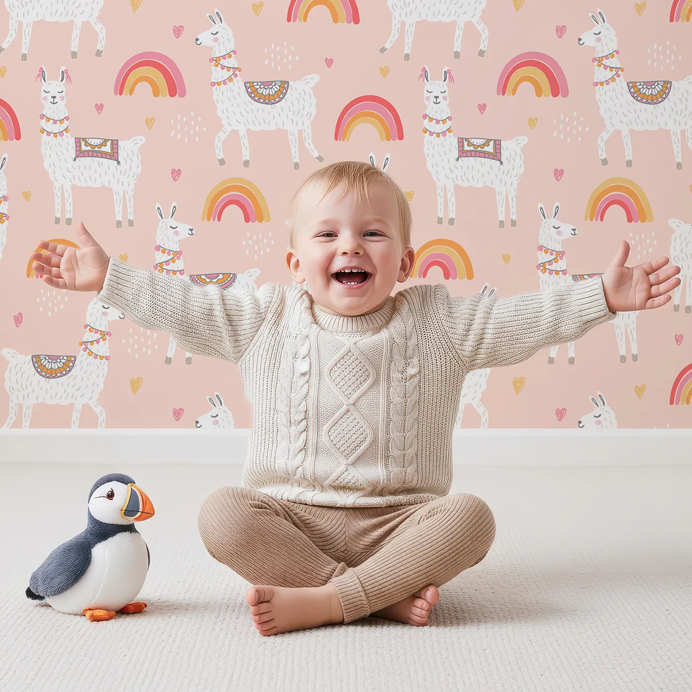Lovely child standing in front of Whimsy Tots Boho Llama Rainbow Wallpaper in Pink with llama, rainbow, heart, boho, animal in design.