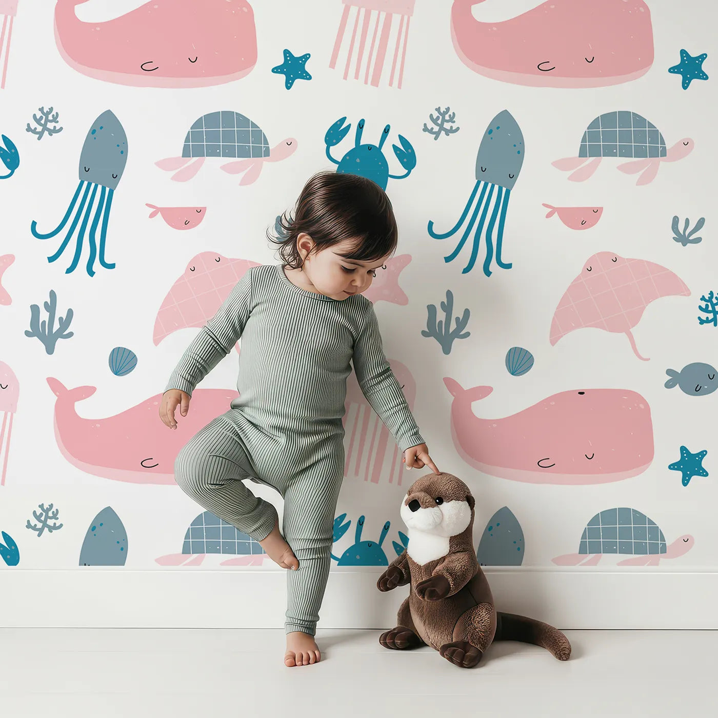 Lovely child standing in front of Whimsy Tots Pastel Ocean Friends Wallpaper with ocean, whale, turtle, jellyfish, sea in design.