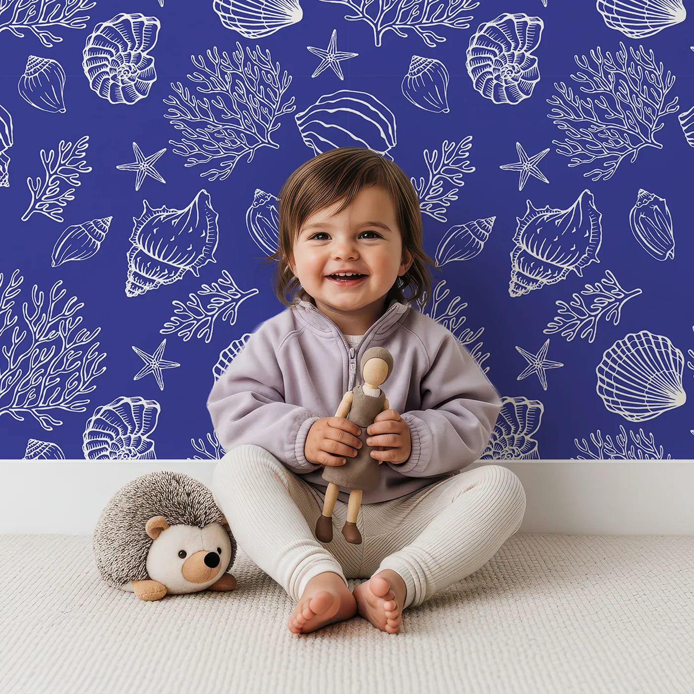 Lovely child standing in front of Whimsy Tots Seashell Sketch Wallpaper in Blue with shell, coral, starfish, ocean, sea in design.