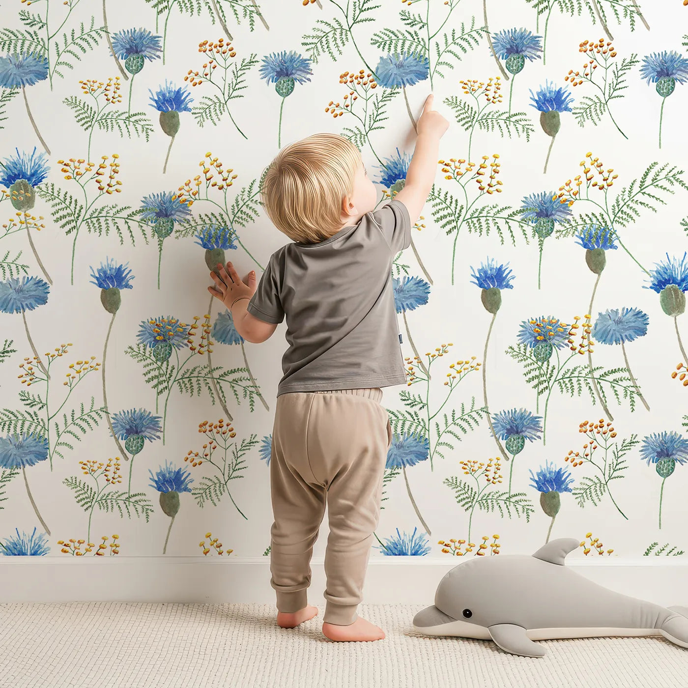 Lovely child standing in front of Whimsy Tots Watercolor Wildflower Meadow Wallpaper with flower, wildflower, cornflower, watercolor, botanical in design.