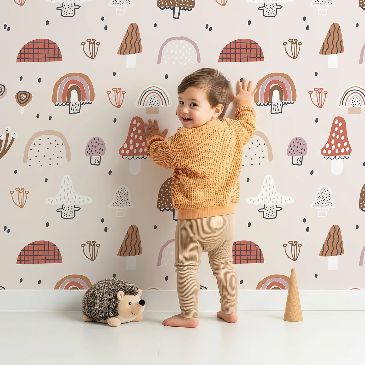 Lovely child standing in front of Whimsy Tots Boho Mushroom Rainbow Wallpaper with mushroom, rainbow, boho, forest, nature in design.