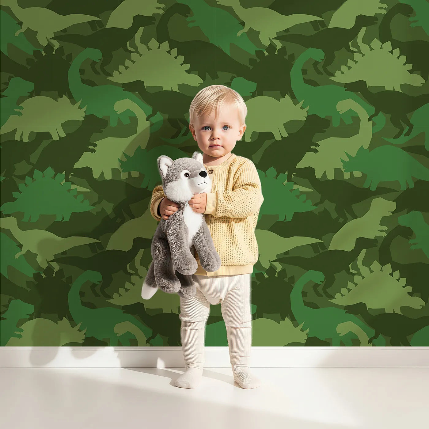 Lovely child standing in front of Whimsy Tots Dinosaur Camouflage Wallpaper in Green with dinosaur, camouflage, t-rex, stegosaurus, silhouette in design.