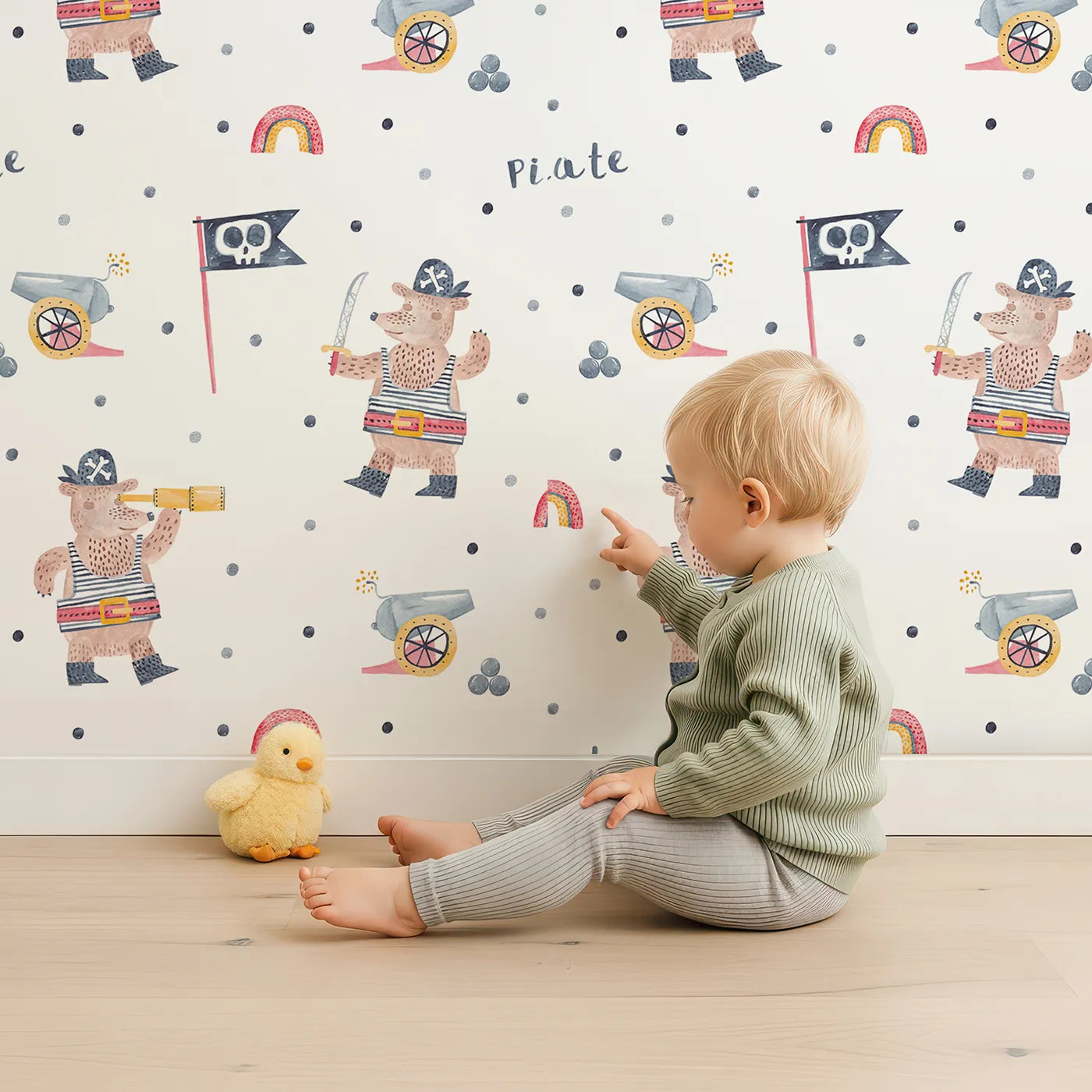 Lovely child standing in front of Whimsy Tots Pirate Bear Adventure Wallpaper with pirate, bear, ship, cannon, rainbow in design.