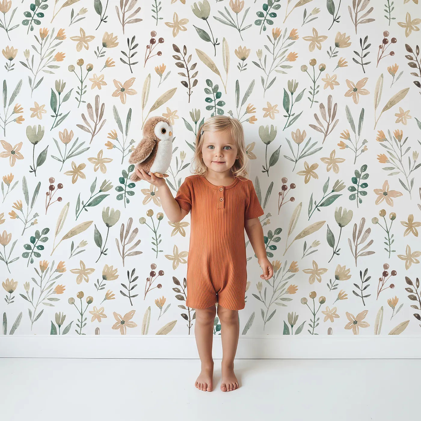 Lovely child standing in front of Whimsy Tots Earthy Watercolor Wildflowers Wallpaper with flower, floral, watercolor, botanical, earth tone in design.