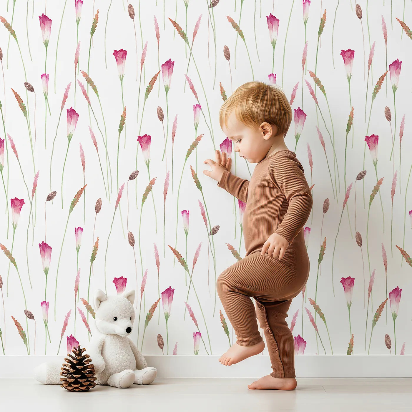 Lovely child standing in front of Whimsy Tots Watercolor Wild Grasses Wallpaper with flower, grass, watercolor, botanical, pink in design.