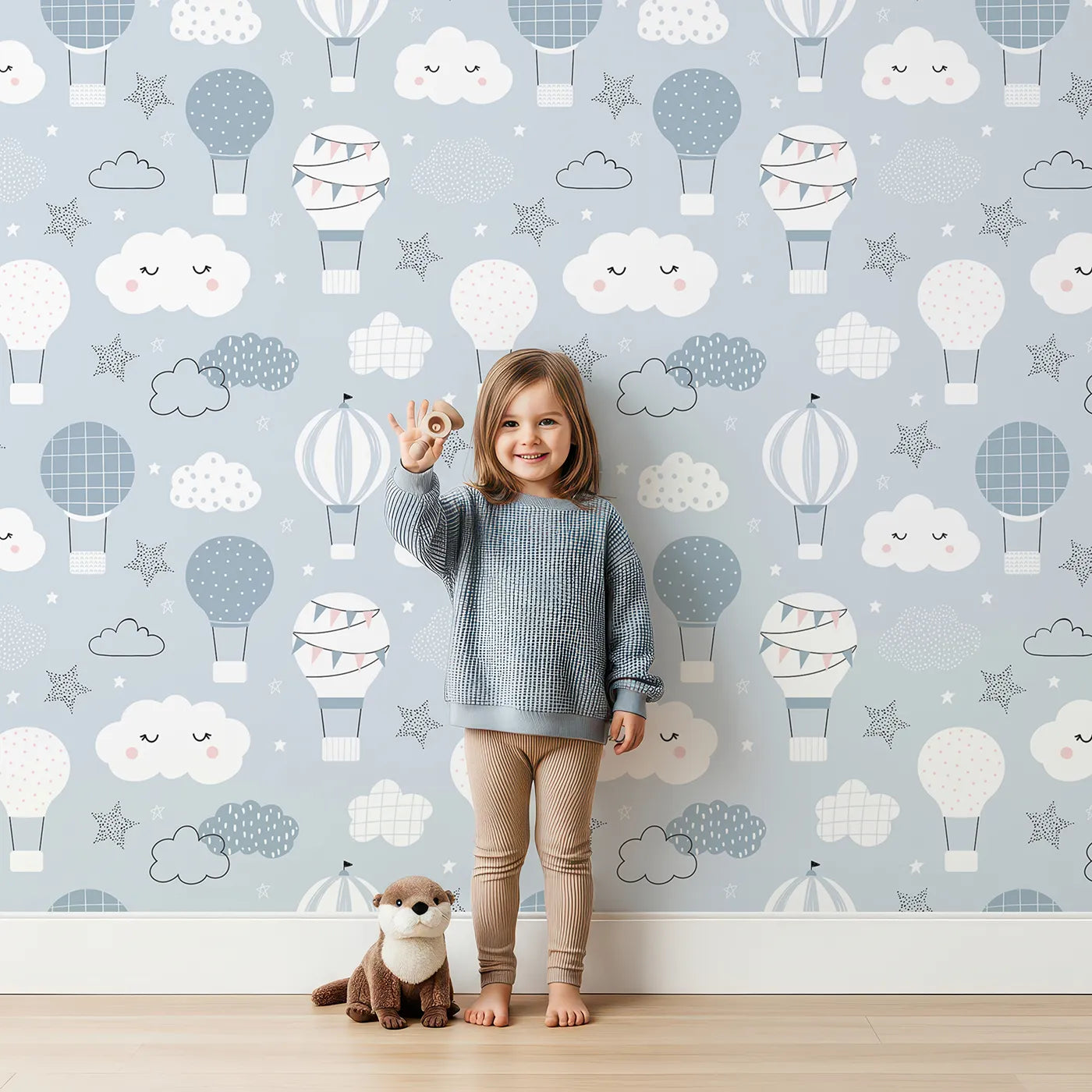 Lovely child standing in front of Whimsy Tots Dreamy Hot Air Balloon Sky Wallpaper with hot air balloon, cloud, star, sky, blue in design.